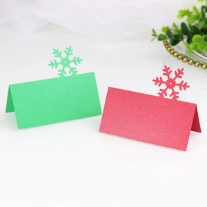Elegant laser-cut snowflake place cards in red and green pearlescent paper for tables