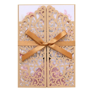 Detail of laser-cut gold wedding invitation with silk bow and floral liner card