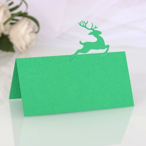 Macro detail of laser-cut green reindeer place card on pearl paper for holiday tables