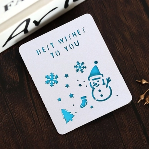 Macro detail of laser-cut snowman and Christmas trees on a blue and white gift card