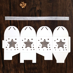 Flat lay of white star-shaped laser-cut gift box template with silver ribbon and dried flower