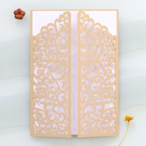 Detail of laser-cut champagne gold wedding invitation with intricate vine patterns