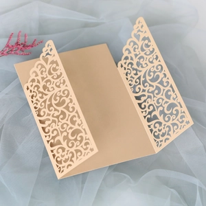 Detail of laser-cut champagne gold wedding invitation with intricate scroll patterns