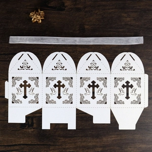 Laser-cut white gift box with cross and dove patterns on a dark wood background