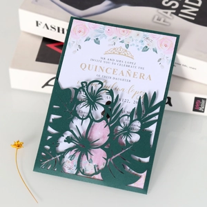 Détail du motif floral découpé au laser sur invitation vert foncé avec couronne dorée