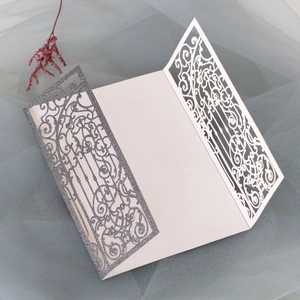 Detail of laser-cut wedding invitation with silver glitter finish and scroll patterns