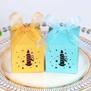 Detail of laser-cut star patterns on yellow and blue gift boxes with organza ribbons
