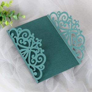 Close-up of laser-cut European floral patterns on dark green wedding invitation card
