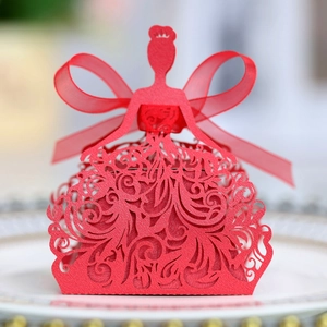 Detail of red laser-cut bride-shaped gift box with silk ribbon on elegant porcelain plate