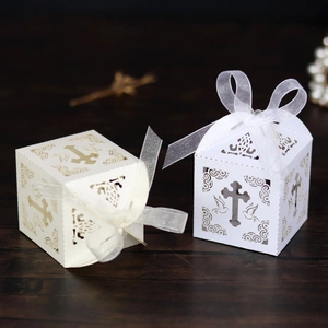 Detailed laser-cut white cross favor box with elegant white organza ribbon bow decoration