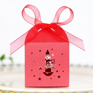 Detail of red laser-cut star gift box with ribbon bow on white ceramic tray