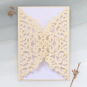 Detailed laser-cut cream wedding invitation cover with intricate scroll patterns and blank insert