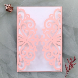 Detailed laser-cut pink wedding invitation with ornate patterns and white inner card