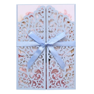 Detailed laser-cut blue wedding invitation with pink floral insert and silk ribbon
