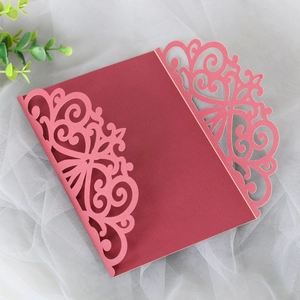 Detail of laser-cut intricate vine patterns on elegant burgundy invitation card sleeves