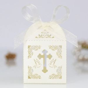 Detail of laser-cut cross design on white favor box with elegant satin ribbon