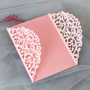 Detail of pink laser-cut wedding invitation featuring elegant European scrollwork pattern
