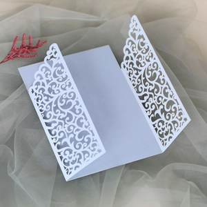 Macro detail of white laser-cut wedding invitation cover with elegant scroll pattern