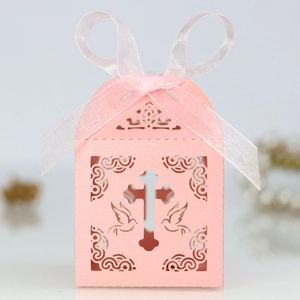 Close-up of laser-cut pink gift box with hollow cross and bird pattern with ribbon