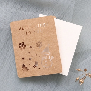 Detail of laser-cut Christmas card with snowman motifs and Best Wishes text on kraft paper