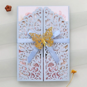 Detail of light blue laser-cut invitation card with golden butterfly and silk ribbon