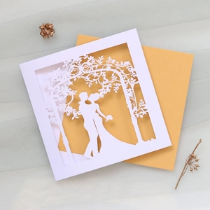 Close-up of laser-cut wedding invitation featuring a romantic couple silhouette