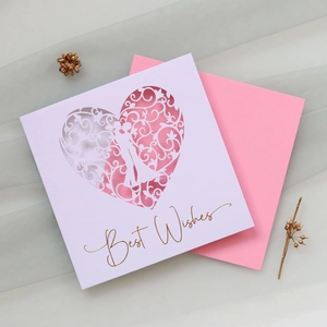 Macro view of laser-cut floral heart greeting card with pink envelope and gold lettering