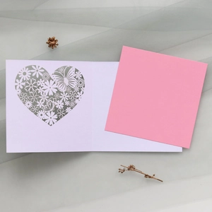 Close-up of laser-cut hollow heart and butterfly patterns on greeting card