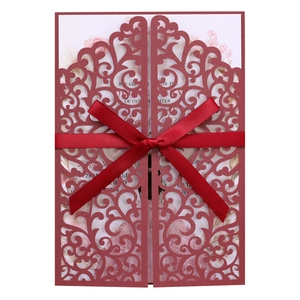 Close-up of laser cut burgundy wedding invitation with intricate floral vine patterns
