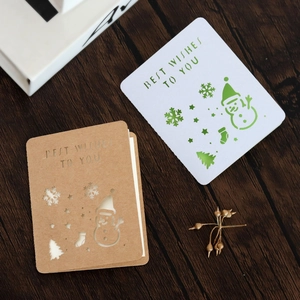 Detail of laser-cut Christmas cards with snowmen and snowflakes on wooden background