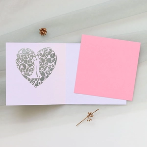 Detailed laser-cut heart silhouette card with floral pattern on soft pink paper