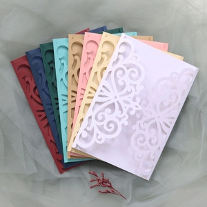 Detailed laser-cut scrollwork on wedding invitation envelopes in various elegant colors