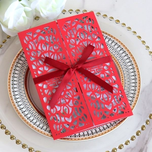 Macro detail of red laser-cut wedding card with silk ribbon on elegant marble