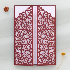 Detail of laser-cut wedding invitation with burgundy vine hollow pattern and ribbon