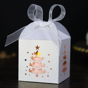Close-up of white pearlescent Christmas tree cutout gift box with white organza ribbon bow