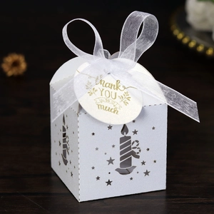 Detail of laser-cut candle and star patterns on a white gift box with Thank You tag