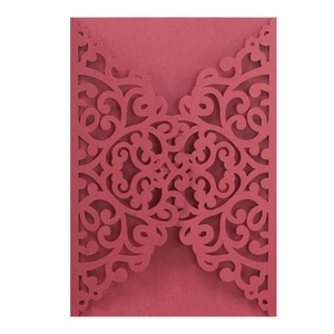 Detail of red laser-cut invitation cover with intricate vintage floral patterns