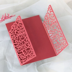 Close-up of burgundy laser-cut lace floral pattern on elegant wedding invitation