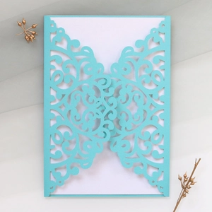Detailed laser-cut vine patterns on a light blue wedding invitation card with white inner sheet