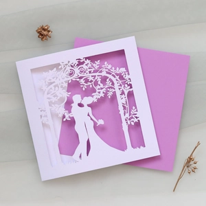 Detail of laser-cut wedding invitation featuring a romantic couple under floral arch