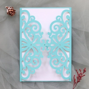 Detail of laser-cut light blue wedding invitation with elegant scroll patterns