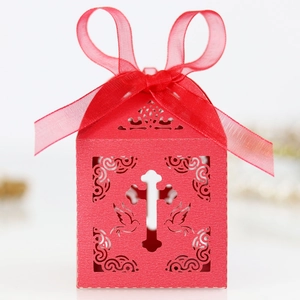 Detail of red laser-cut candy box with cross and dove patterns and a silk ribbon bow
