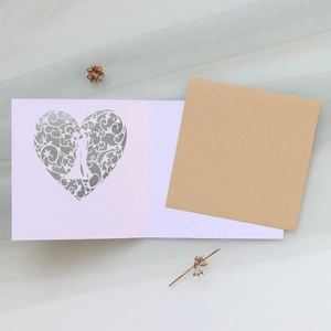 Detailed laser-cut heart and couple silhouette on an elegant pink greeting card