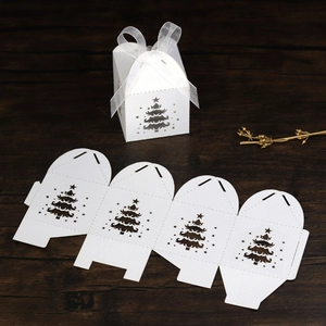 Detail of white laser-cut Christmas tree candy box with flat layout and organza ribbon