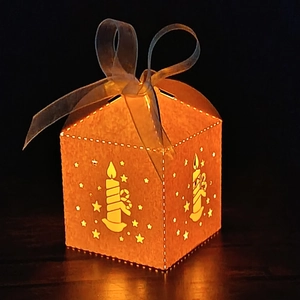 Detail of laser-cut star pattern on a glowing Christmas gift box with ribbon