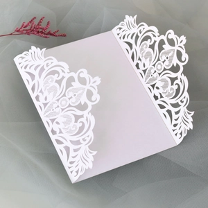 Détail des motifs de dentelle florale découpés au laser sur l'invitation de mariage