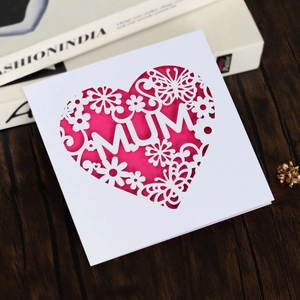 Macro detail of laser-cut heart greeting card with MUM text and butterfly on wood