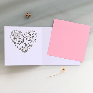 Detailed laser-cut heart and butterfly patterns on elegant white and pink greeting cards