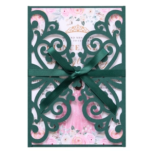 Macro detail of laser-cut forest green lace envelope with satin bow and floral inner card