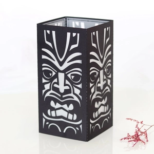 Detail of laser-cut black cardboard Tiki mask lantern cover with hollow mask patterns
